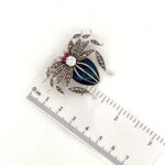 Sterling silver spider brooch with enamel, marcasite and crystals, shown beside a ruler.